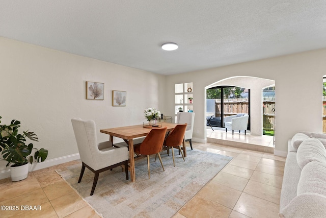 208 Pine Cone Trl, Ormond Beach, FL 32174 - dining space featuring light tile patterned floors, arched walkways, baseboards, and a textured ceiling