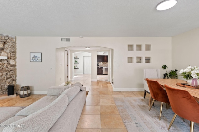 208 Pine Cone Trl, Ormond Beach, FL 32174 - living room featuring arched walkways, baseboards, light tile patterned flooring, and a textured ceiling