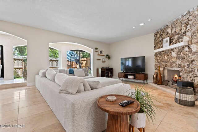 208 Pine Cone Trl, Ormond Beach, FL 32174 - tiled living room with a stone fireplace, recessed lighting, and a textured ceiling