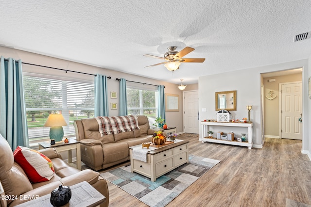 living room featuring ceiling fan, a textured ceiling, and light wood-type flooring