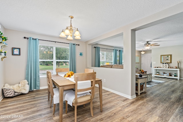 dining space featuring ceiling fan with notable chandelier, wood-type flooring, and a textured ceiling