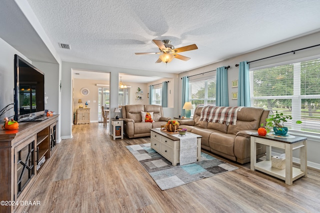 living room with a textured ceiling, light hardwood / wood-style floors, and ceiling fan