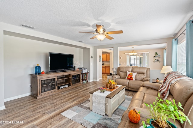 living room featuring a textured ceiling, light hardwood / wood-style flooring, and ceiling fan with notable chandelier