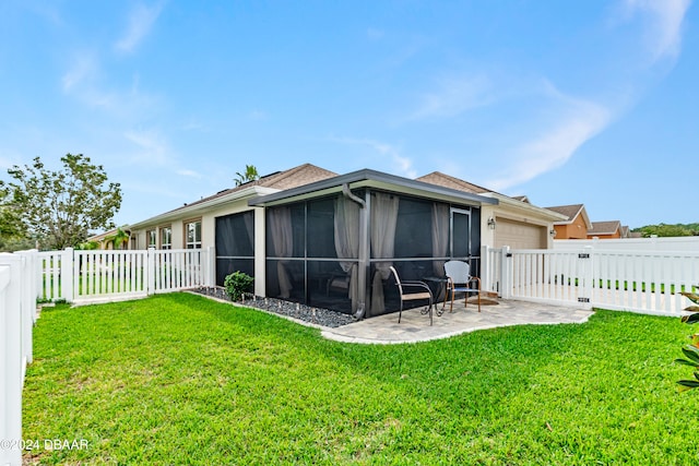 back of property featuring a yard, a patio area, and a sunroom