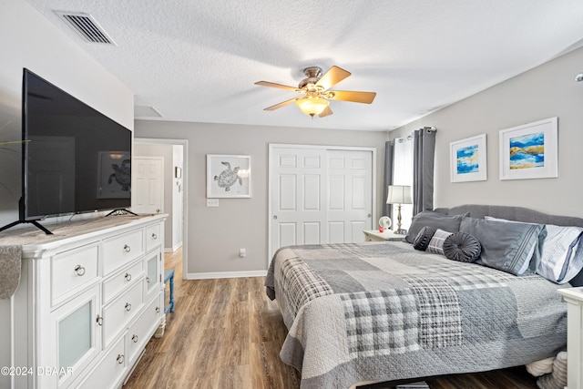 bedroom featuring hardwood / wood-style floors, a textured ceiling, a closet, and ceiling fan