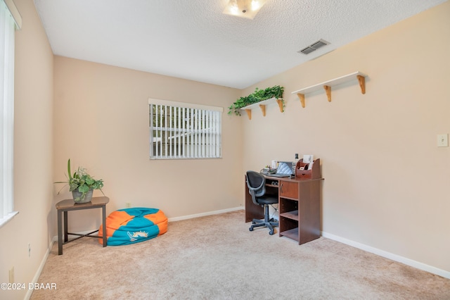 carpeted home office featuring a textured ceiling