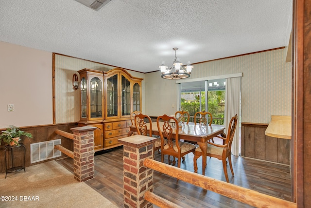 dining room with a chandelier, a textured ceiling, dark hardwood / wood-style flooring, and crown molding