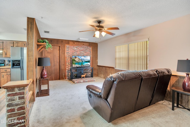 living room with wooden walls, ceiling fan, light colored carpet, and a textured ceiling