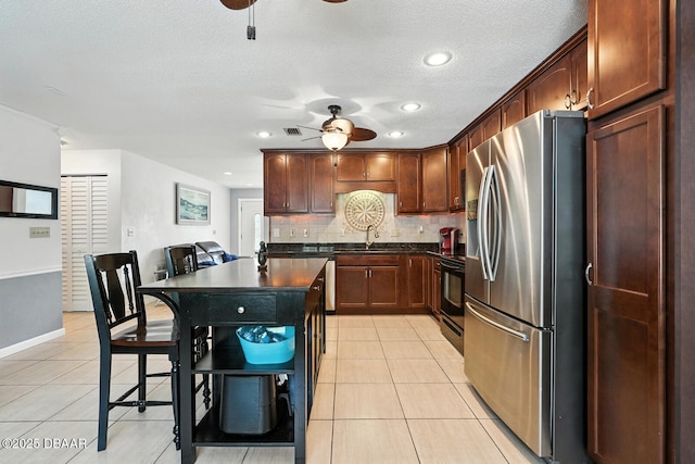 1720 Hope Dr, Ormond Beach, FL 32174 - kitchen featuring stainless steel appliances, ceiling fan, dark countertops, light tile patterned floors, and tasteful backsplash