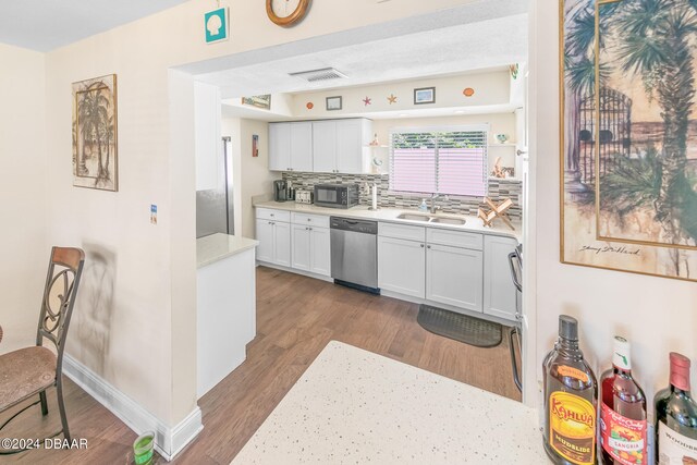 kitchen featuring wood-type flooring, dishwasher, sink, backsplash, and white cabinetry