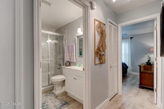 bathroom featuring vanity, toilet, and a shower with door