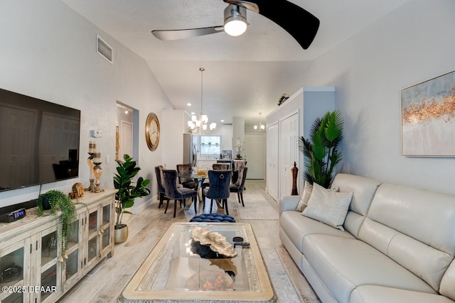 living room with ceiling fan with notable chandelier and lofted ceiling