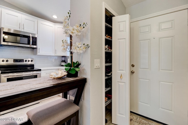 kitchen featuring white cabinets, a breakfast bar area, appliances with stainless steel finishes, and tasteful backsplash