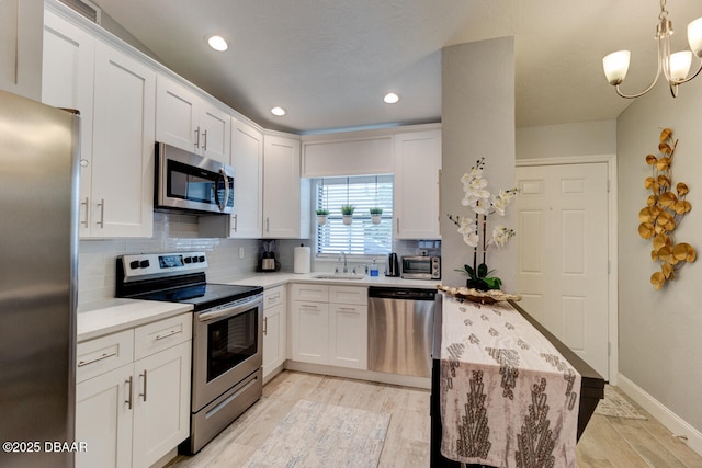 kitchen with decorative backsplash, stainless steel appliances, white cabinetry, and sink