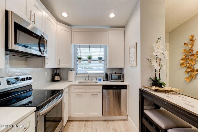 kitchen featuring white cabinets, sink, appliances with stainless steel finishes, and tasteful backsplash