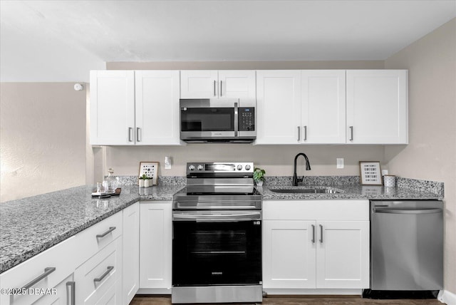 461 Brentwood Dr, Daytona Beach, FL 32117 - kitchen with appliances with stainless steel finishes, white cabinetry, light stone counters, and wood finished floors