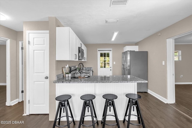 461 Brentwood Dr, Daytona Beach, FL 32117 - kitchen with stainless steel appliances, dark wood finished floors, a peninsula, white cabinetry, and a breakfast bar area