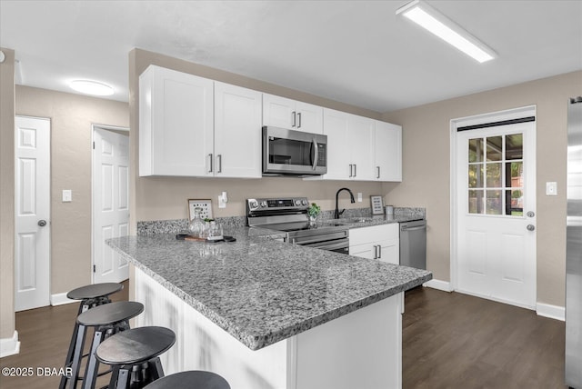 461 Brentwood Dr, Daytona Beach, FL 32117 - kitchen with stainless steel appliances, dark wood-type flooring, a breakfast bar area, and white cabinetry