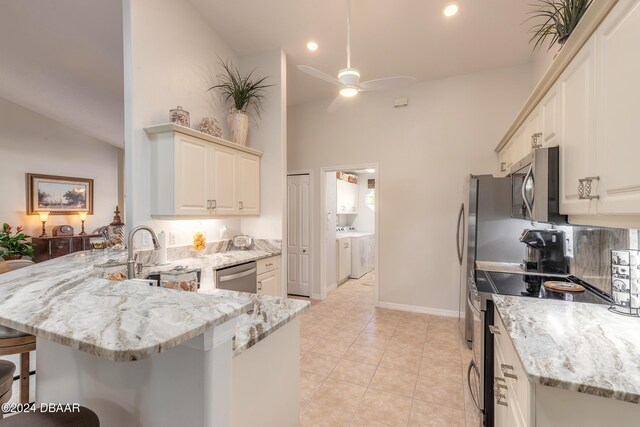 5452 Saint Regis Way, Port Orange, FL 32128 - kitchen featuring stainless steel appliances, separate washer and dryer, a peninsula, a breakfast bar, and light stone counters