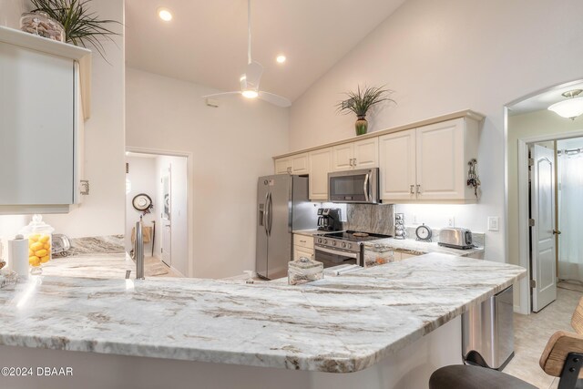 5452 Saint Regis Way, Port Orange, FL 32128 - kitchen featuring stainless steel appliances, light stone counters, high vaulted ceiling, a peninsula, and a ceiling fan