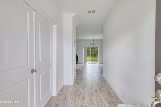 corridor featuring light hardwood / wood-style flooring and an inviting chandelier