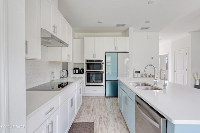 kitchen featuring white cabinetry, stainless steel appliances, a center island with sink, and sink