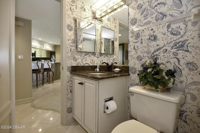 2425 S Atlantic Ave Unit 1403, Daytona Beach, FL 32118 - bathroom with wallpapered walls, toilet, vanity, and baseboards