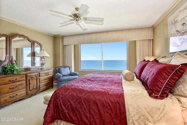 bedroom featuring light carpet, a water view, ceiling fan, a textured ceiling, and crown molding