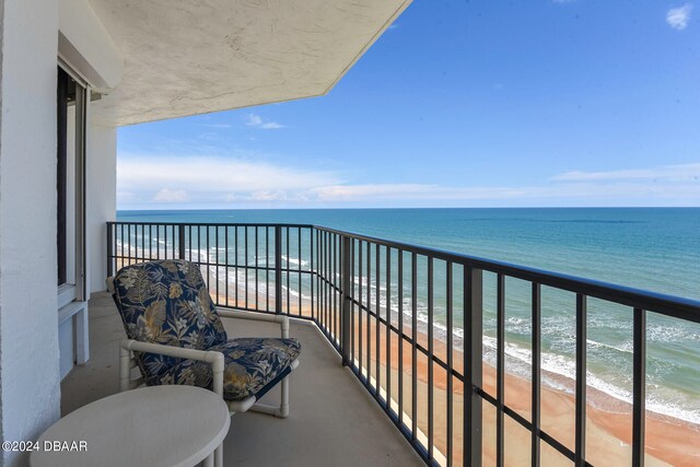 balcony with a water view and a view of the beach