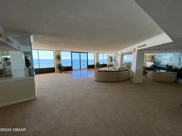 unfurnished living room featuring a water view, a textured ceiling, carpet, and floor to ceiling windows