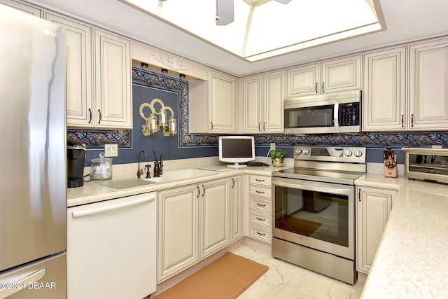 kitchen with stainless steel appliances, sink, ceiling fan, backsplash, and cream cabinetry