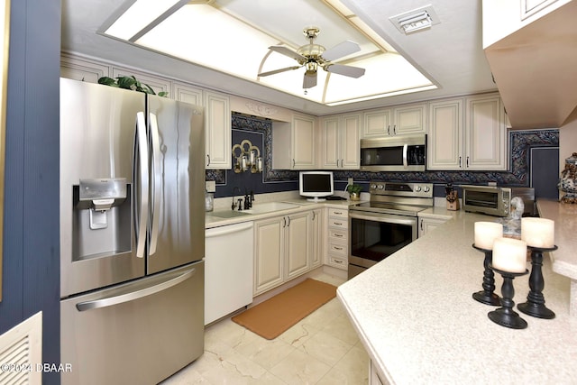 kitchen featuring cream cabinets, sink, ceiling fan, backsplash, and appliances with stainless steel finishes