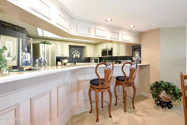 kitchen featuring light stone countertops, stainless steel appliances, light carpet, and a breakfast bar area