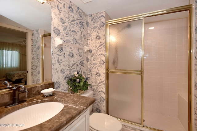 bathroom featuring a shower with shower door, vanity, and toilet