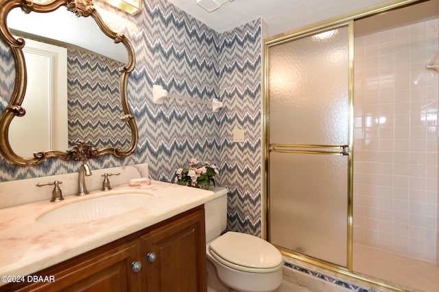 bathroom featuring vanity, toilet, and a shower with shower door