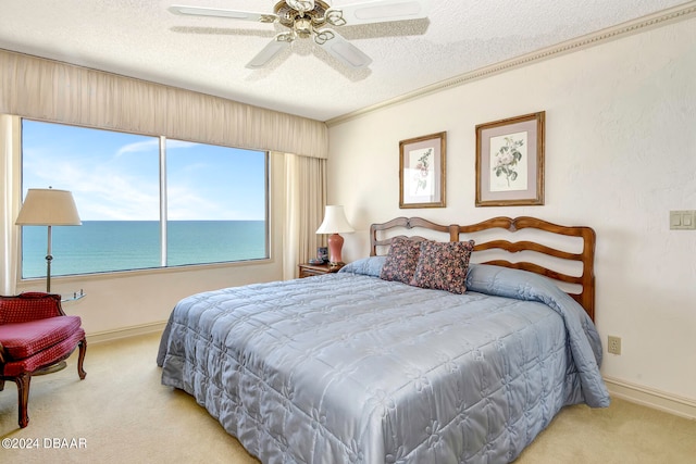 bedroom featuring light carpet, a water view, ceiling fan, a textured ceiling, and crown molding