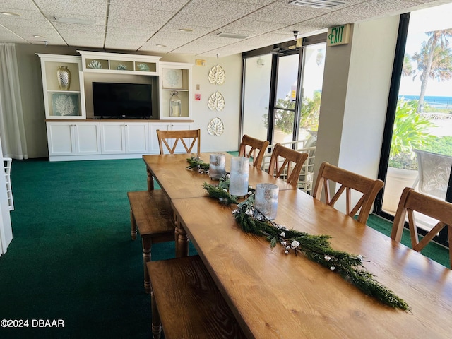 carpeted dining space featuring a drop ceiling and a healthy amount of sunlight