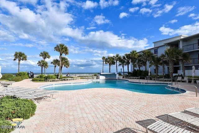 view of pool featuring a water view and a patio area