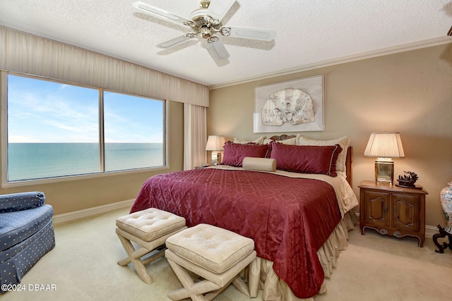 bedroom with a textured ceiling, light colored carpet, a water view, and ceiling fan