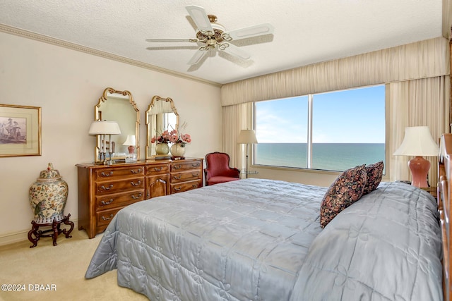 carpeted bedroom with ceiling fan, a textured ceiling, a water view, and crown molding