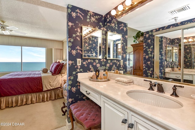 bathroom featuring vanity, ceiling fan, a textured ceiling, and a water view