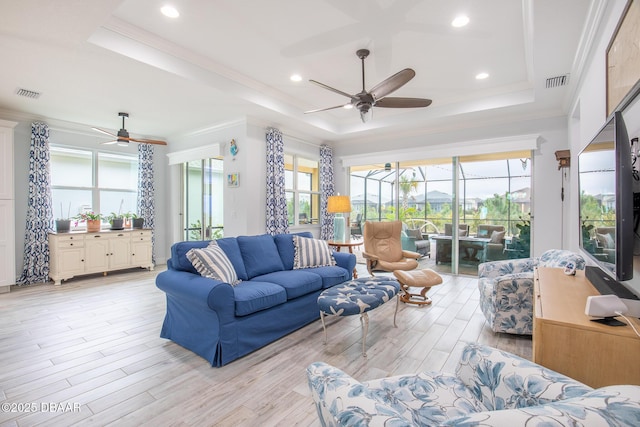 living room featuring ceiling fan, a raised ceiling, crown molding, and light hardwood / wood-style flooring