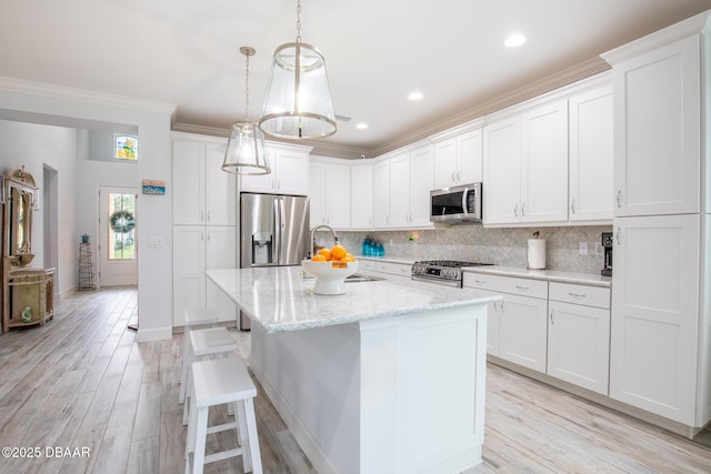 kitchen featuring white cabinets, sink, an island with sink, light stone counters, and stainless steel appliances