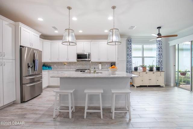 kitchen with white cabinets, stainless steel appliances, light stone counters, and an island with sink