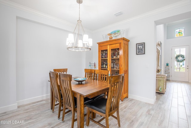 dining room featuring light wood-type flooring, an inviting chandelier, and ornamental molding