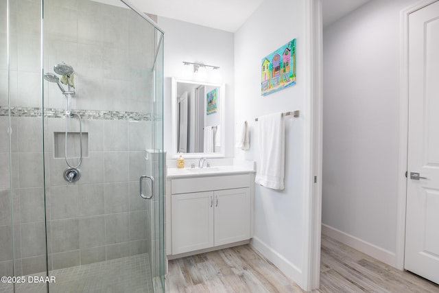 bathroom with wood-type flooring, vanity, and an enclosed shower