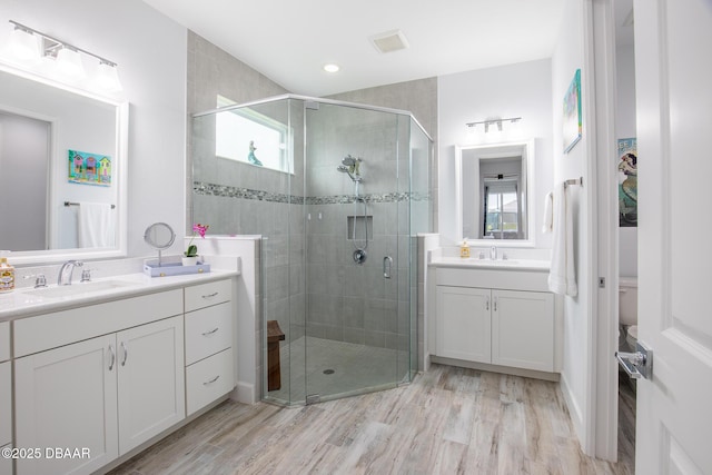 bathroom with hardwood / wood-style floors, vanity, and an enclosed shower