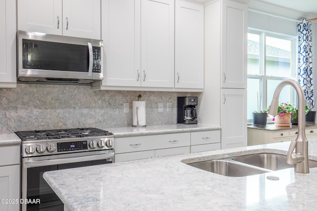 kitchen featuring sink, stainless steel appliances, light stone counters, backsplash, and white cabinets