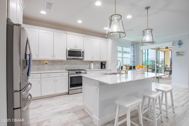 kitchen with appliances with stainless steel finishes, white cabinetry, a kitchen island with sink, and sink