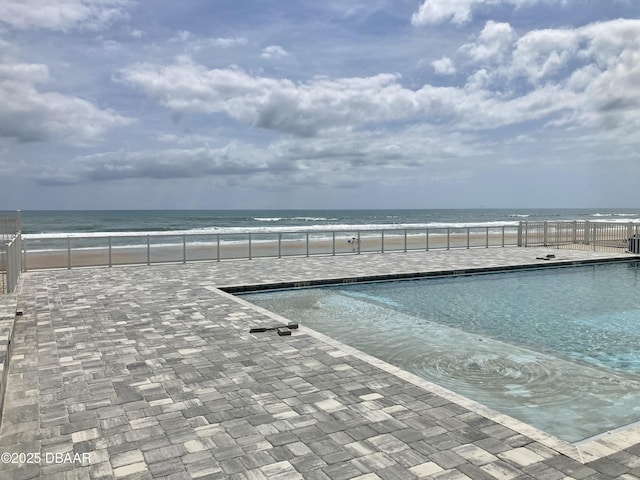 exterior space with a patio, fence, a beach view, and a water view